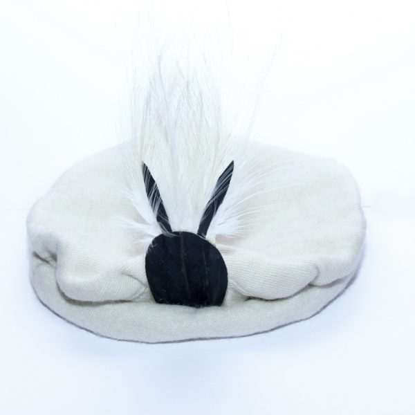 A white woolen cap with a black and white feather on the front side of it